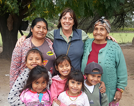 Claudia Valeggia smiles with her arms around two Indigenous women and five children.