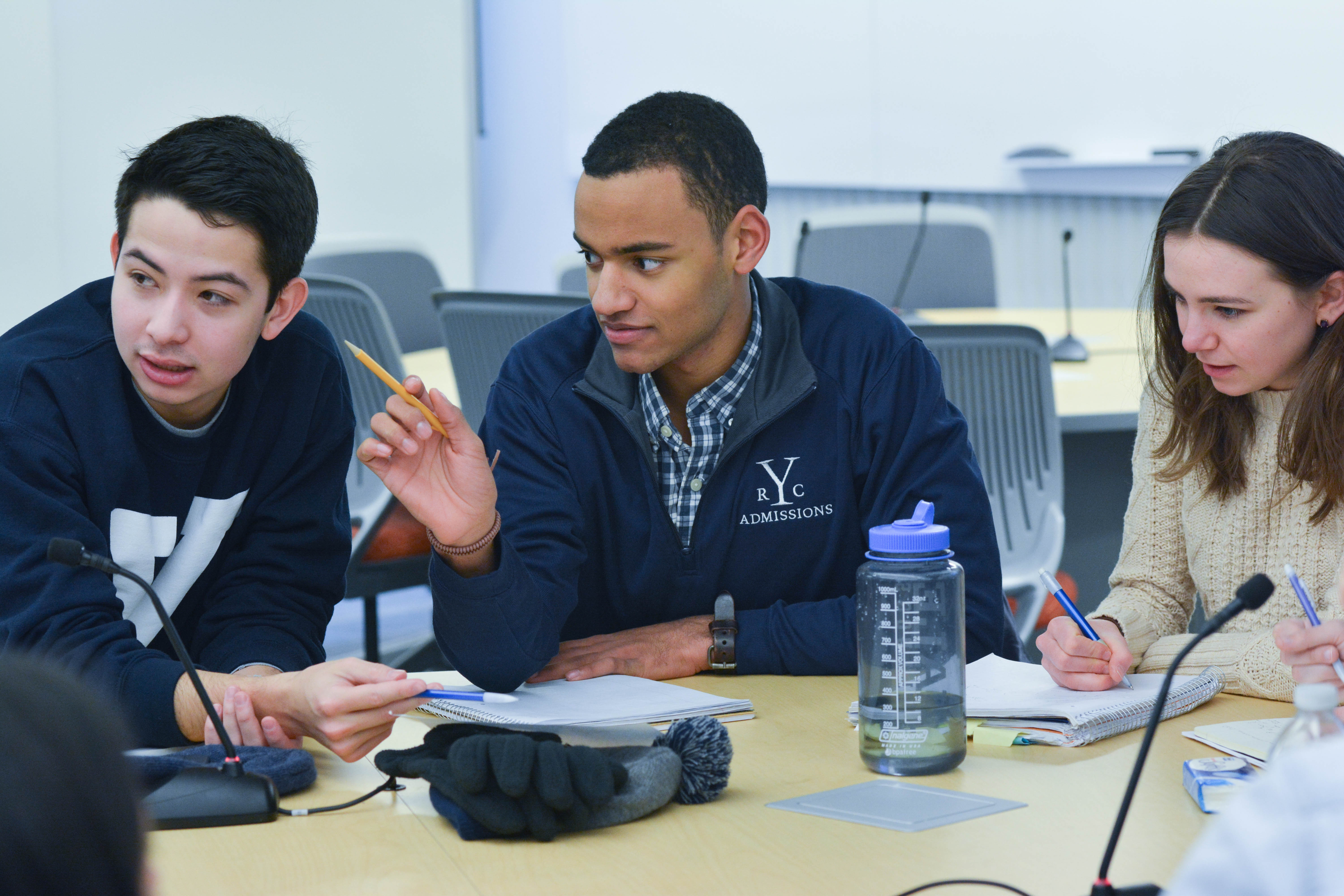 Students at a table listening to a lecture