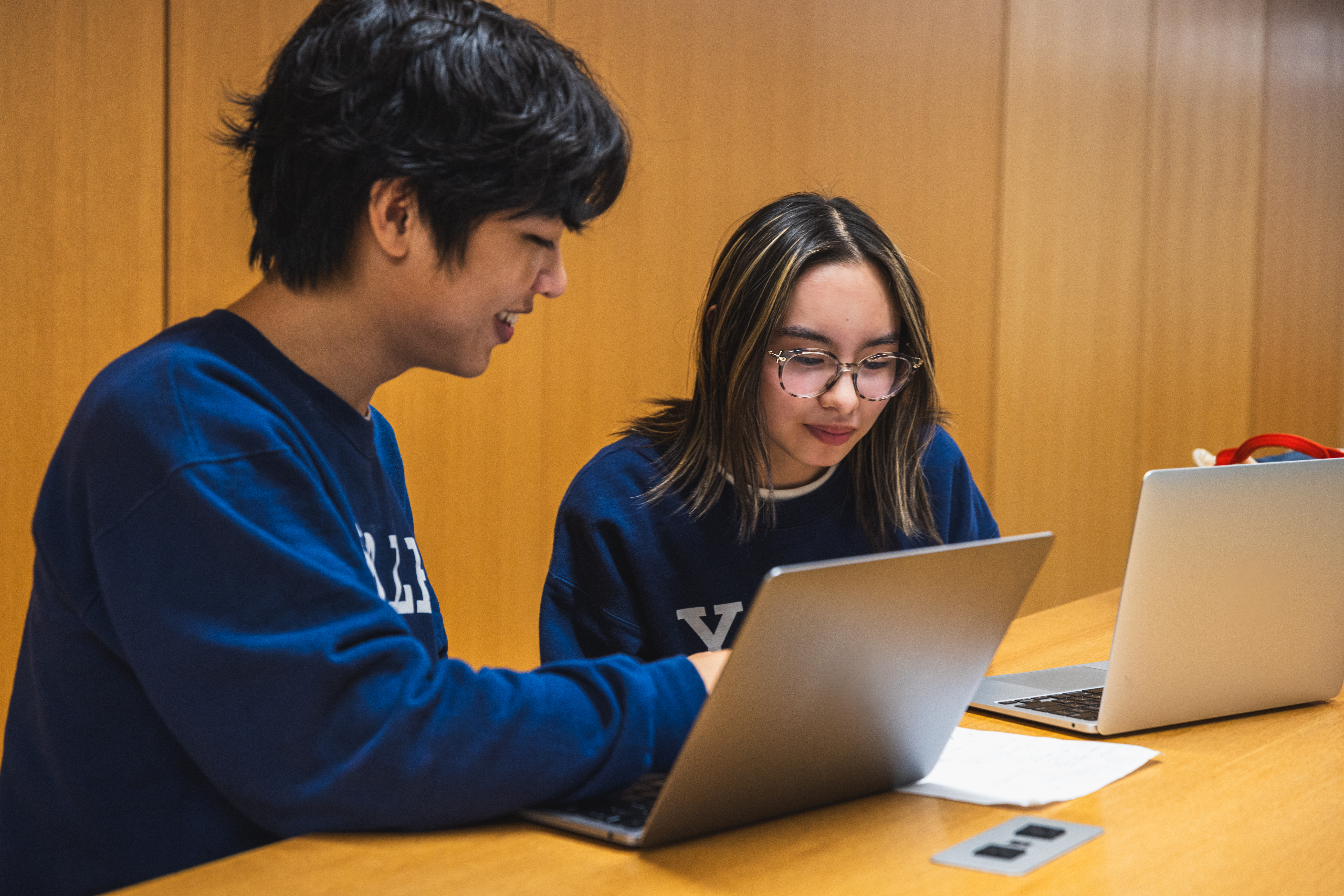 two students working together with laptops