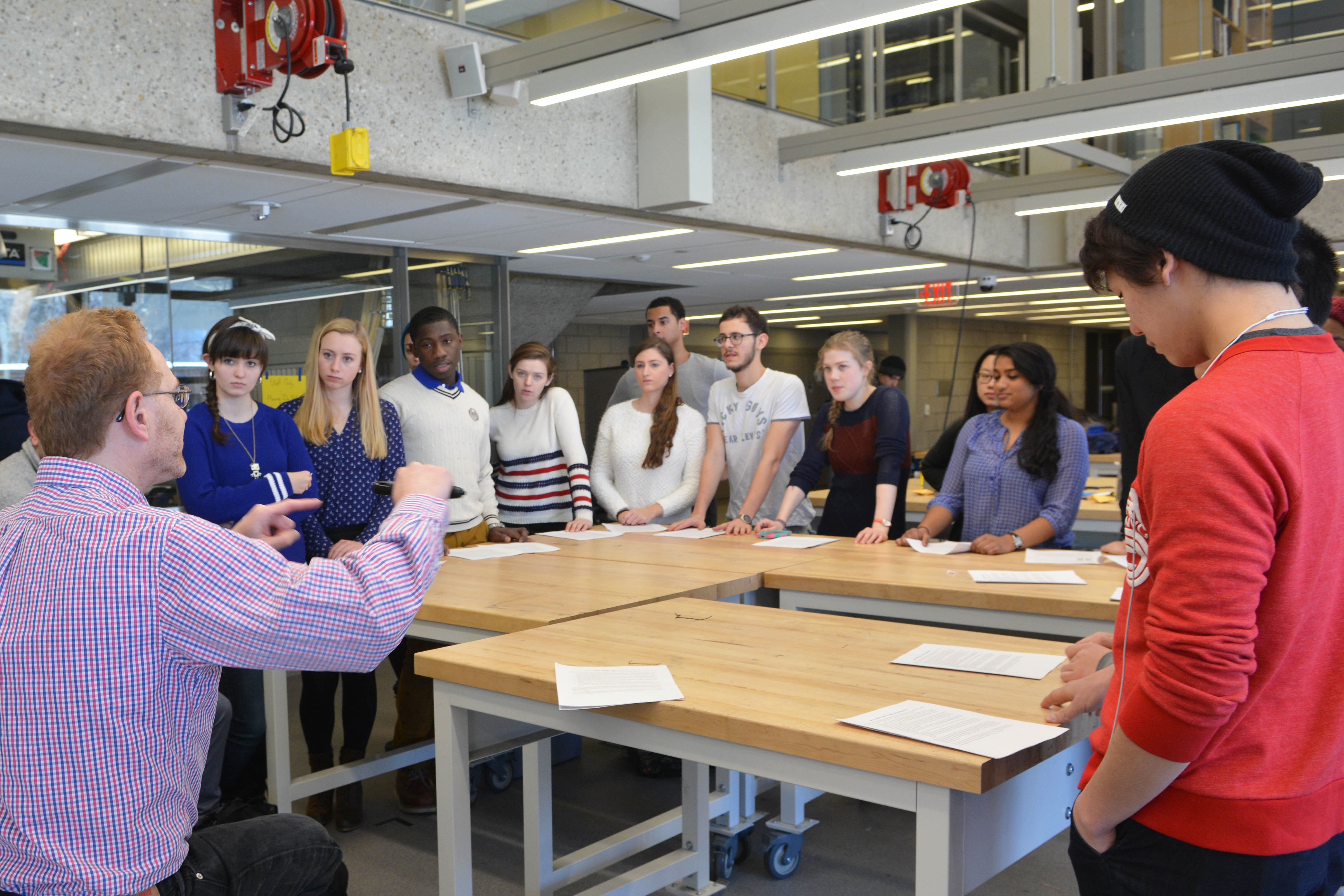 Instructor teaching a class of students standing around a table