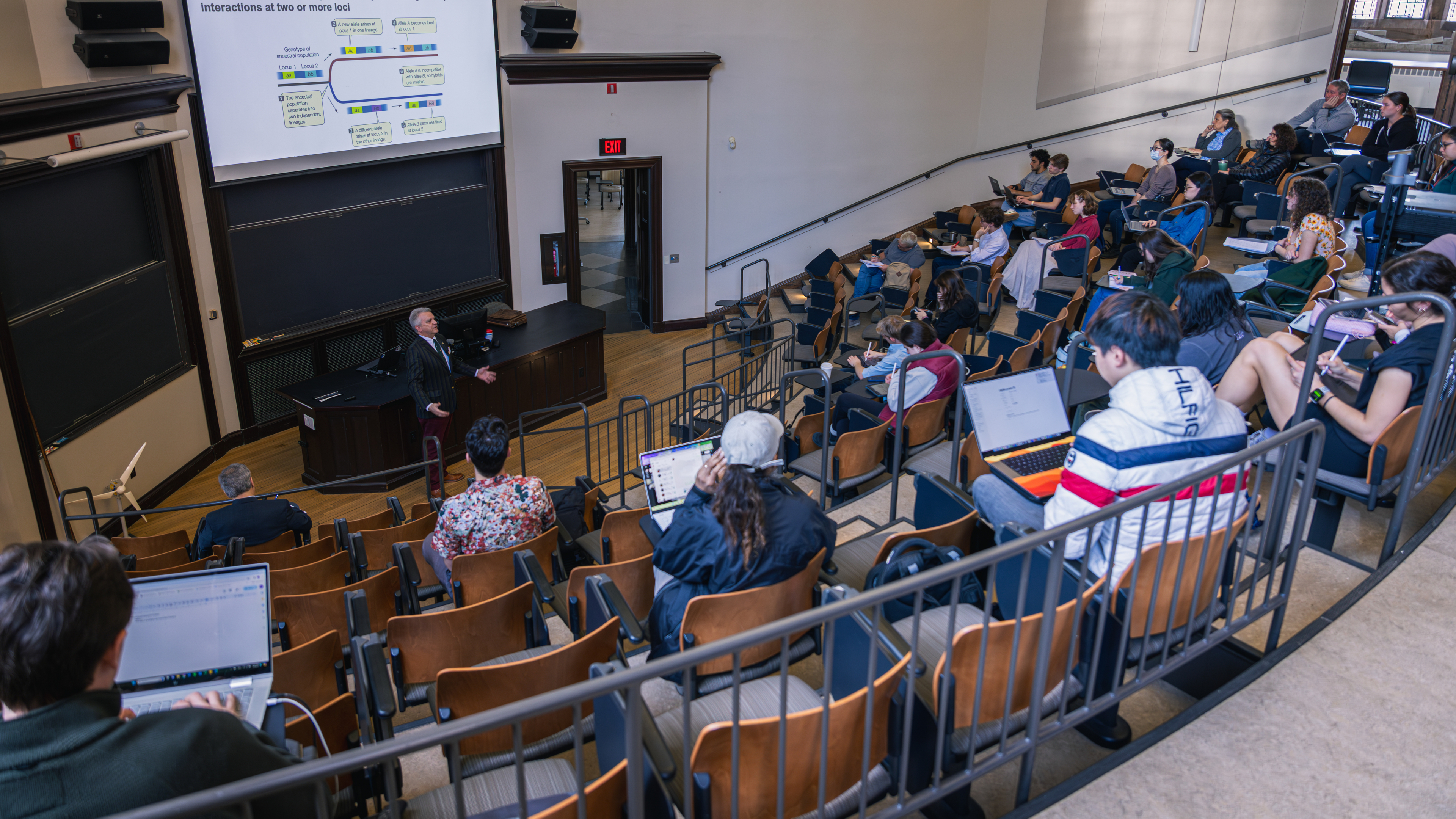 A lecture hall of students watching a presenter.