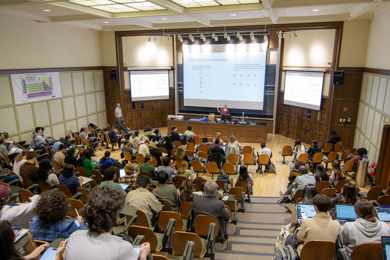 A lecture hall full of students with an instructor in the front of the room