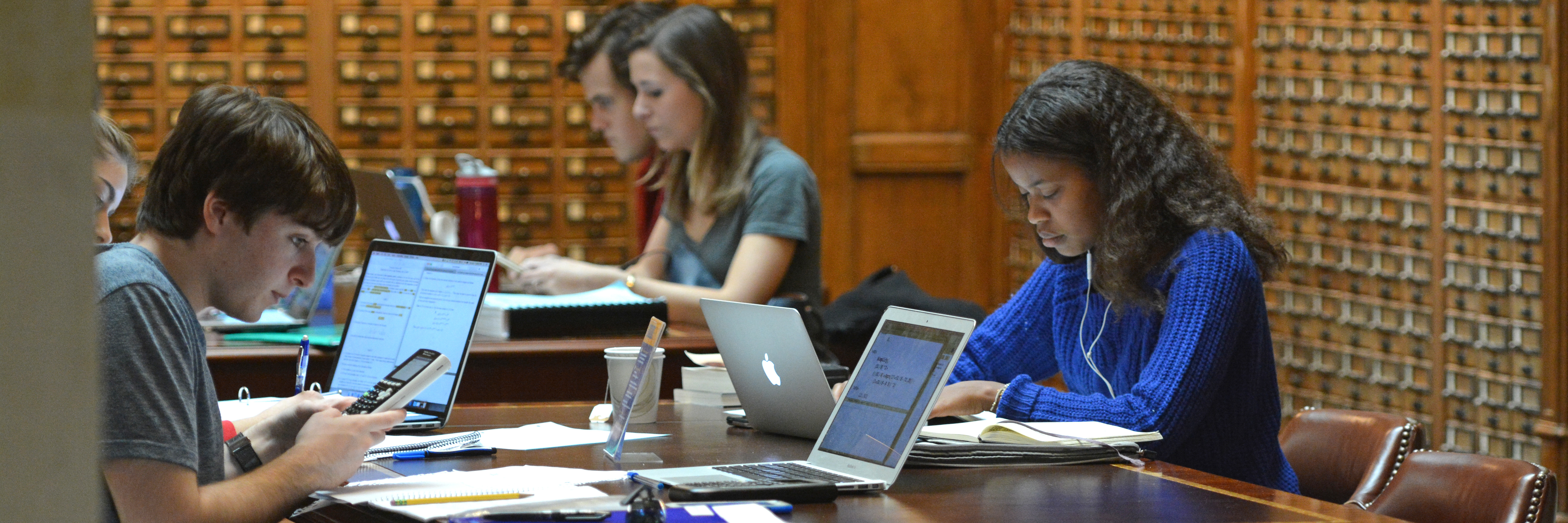 Students writing on laptops near the SML card catalogs.