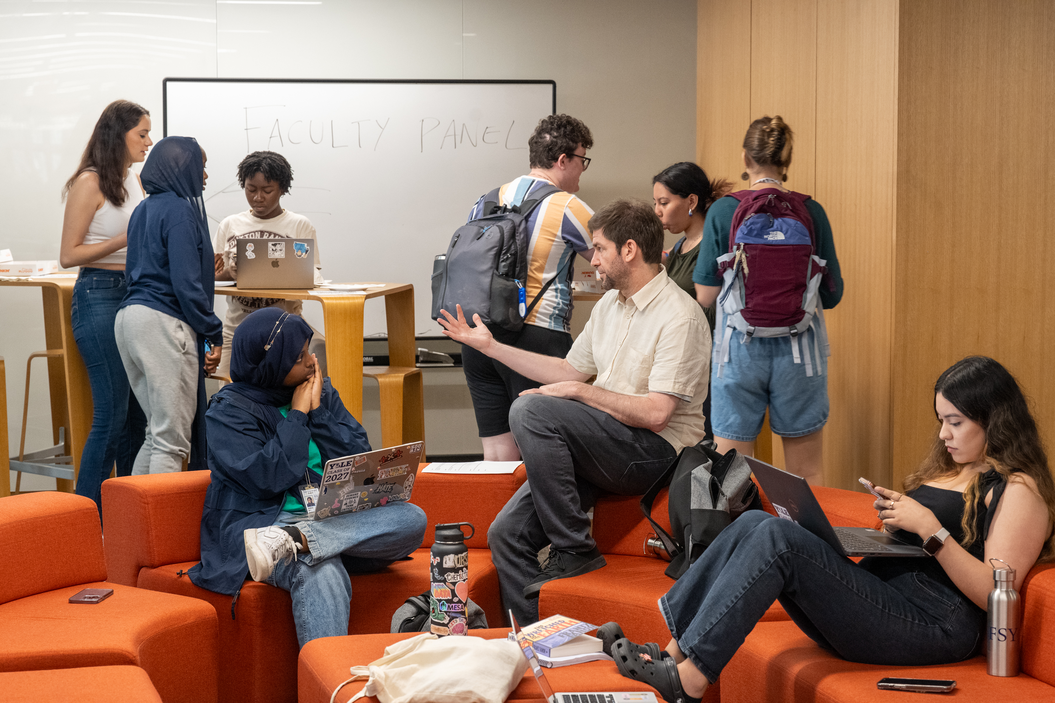 An instructor speaks with a student as other students work together in the common space at the Poorvu Center.