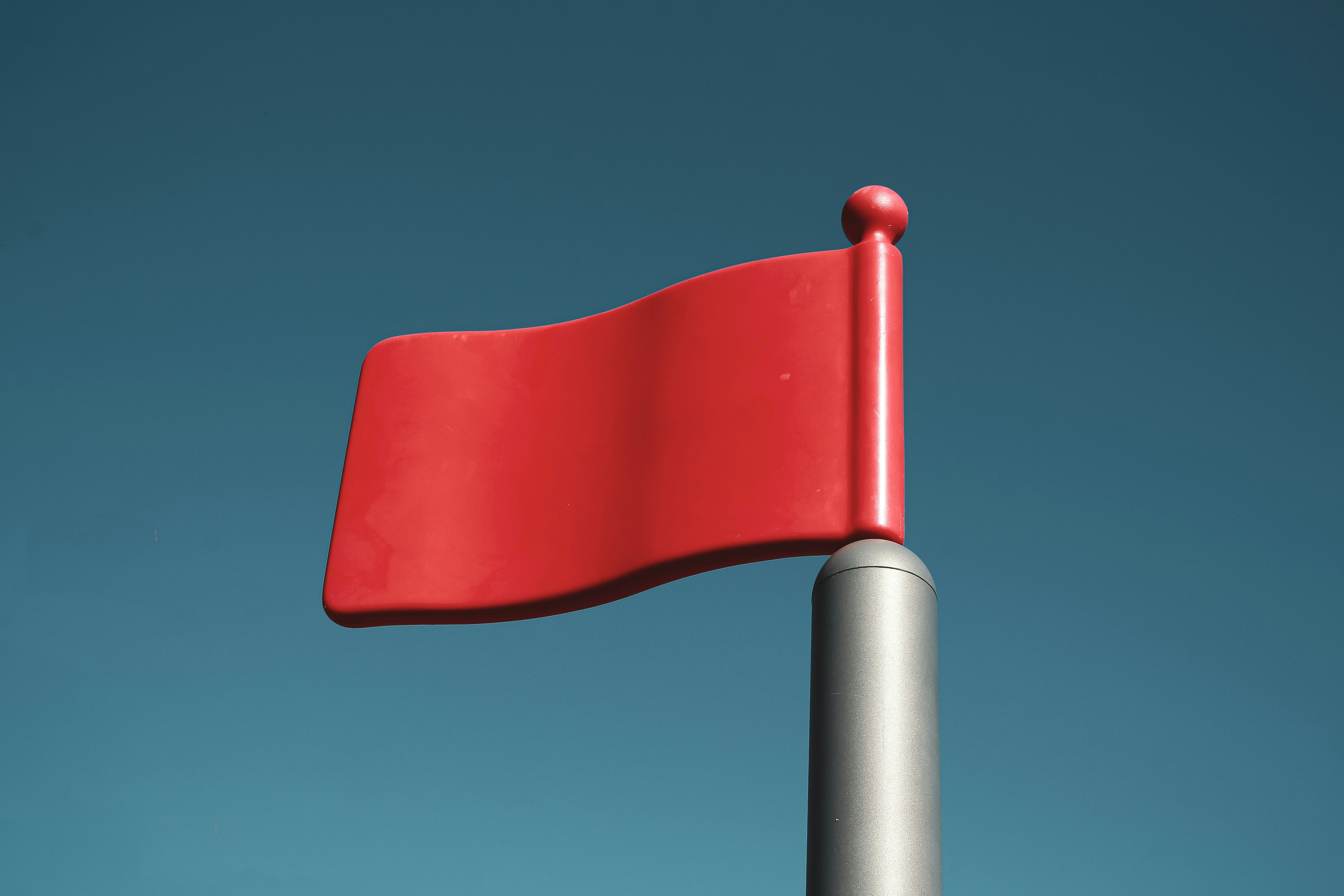 A red flag waving against a blue backdrop