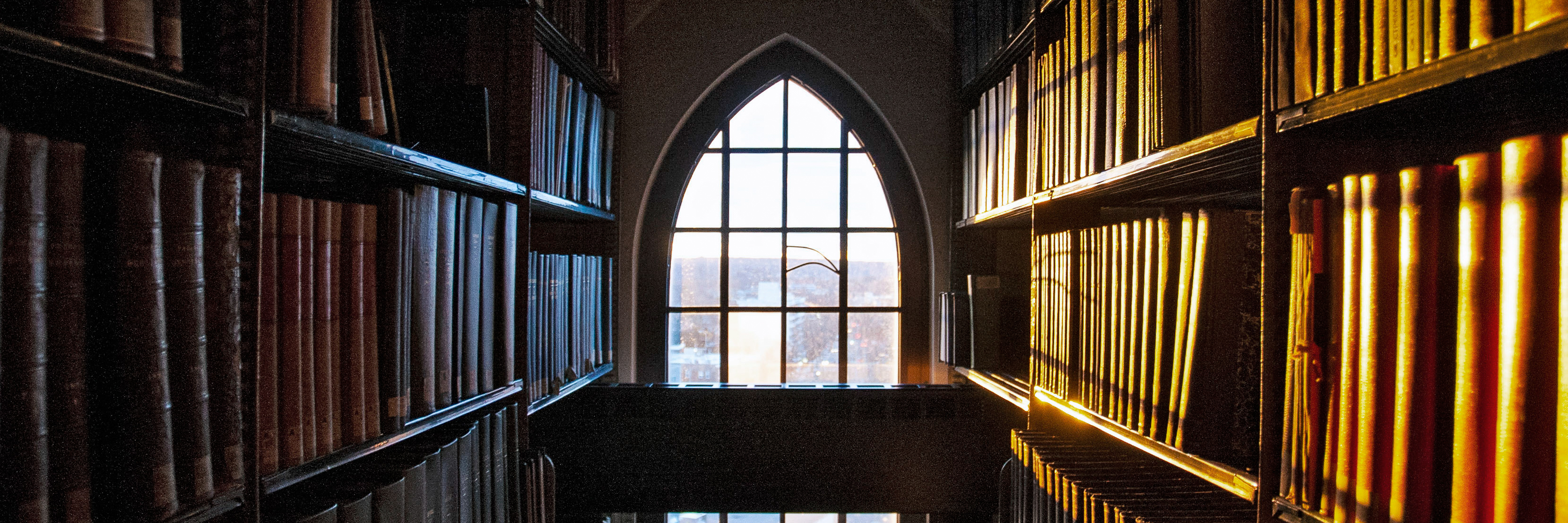Light shining through a window on books in the SML stacks.