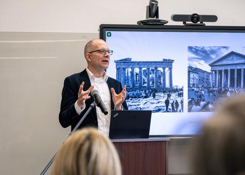 Yale professor presents in front of images of ancient Roman ruins