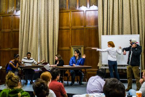 Universityof Michigan CRLT players perform a sketch on a stage in a classroom.