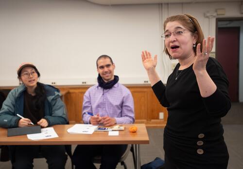 A Yale language instructor exuberantly teaches while smiling students look on. 