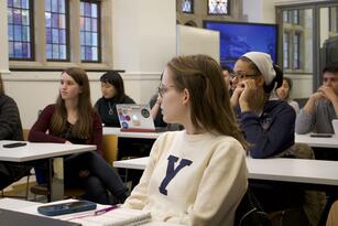 Students sit in class at tables in the Poorvu Center.