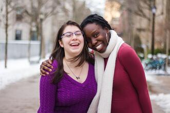 Two FGLI mentors laughing and smiling at the camera on the Yale campus during winter.