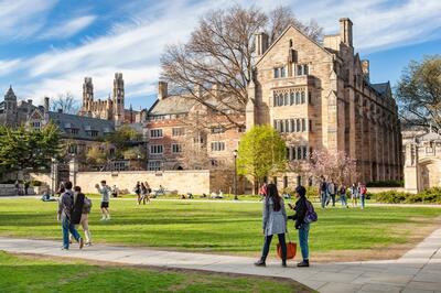 Image of Cross Campus on sunny day, with students walking on the grass and sidewalks.