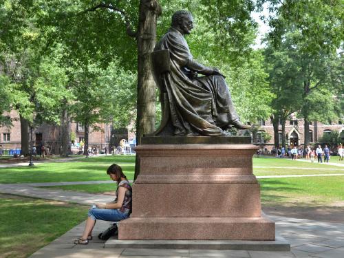 A person rests during Freshmen move-on on a statue in Old Campus at Yale