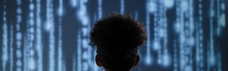 Student is standing away from camera looking at a stream of computer codes