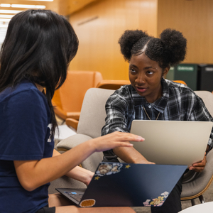 Two students sit with their laptops in the Poorvu Center.