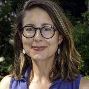 Nichole Gleisner is a woman with glasses, shoulder-length brown hair and wearing a blue top.