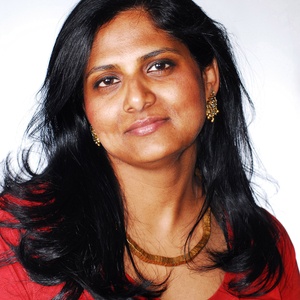 Priyamvada Natarajan is a woman with dark brown hair wearing a red shirt.