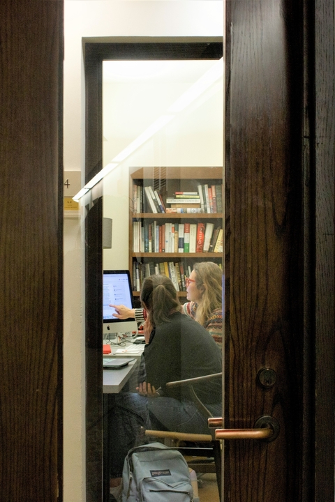A student looks on as a Tutor points to a computer screen in her office.