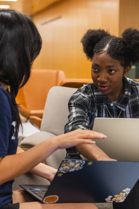 Two students sit with their laptops in the Poorvu Center.