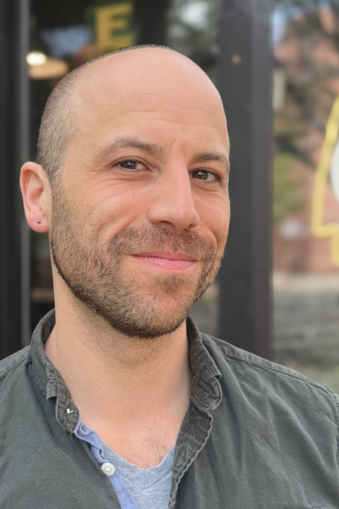 Ben Glaser, the Director of AI Initiatives in the Humanities at the Poorvu Center and Yale Library, poses in front of windows.