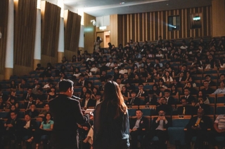 Two grad students presenting research to a large lecture hall.
