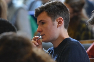 Man at a seminar chewing on a pen cap