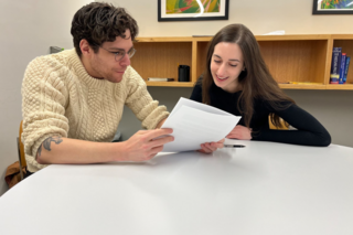 Two people thoughtfully reading some papers.