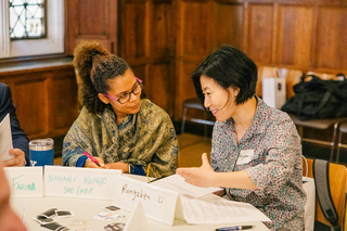 Two faculty members sit at a table having a conversation during Course (Re)Design.