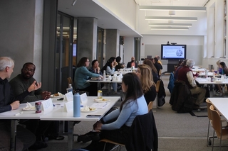 Instructors seated at tables during presentation.