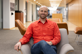 Ben Glaser poses in a chair in the common area of the Poorvu Center.