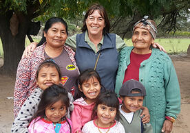 Claudia Valeggia smiles with her arms around two Indigenous women and five children.