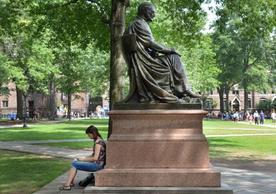 A person rests during Freshmen move-on on a statue in Old Campus at Yale
