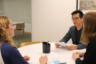Three grad students exchanging feedback on a paper in a Poorvu Center office.