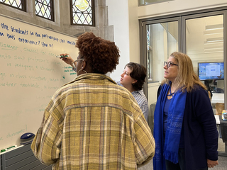 Student and faculty writing at a white board