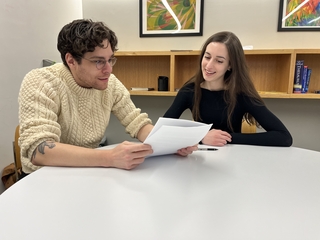 A GWL Fellow and a writer discussing a paper together in a Poorvu Center office.