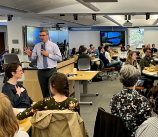 Image of Spring Teaching Forum 2023 with speaker Derek Bruff speaking and participants sitting at round tables