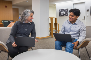 Two people sitting in the Poorvu Center with laptops open