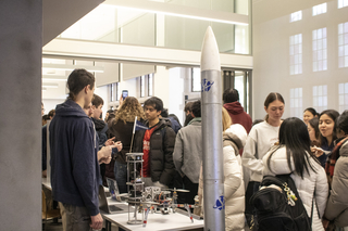 Students talk in a crowded room where STEM clubs showcase their projects.