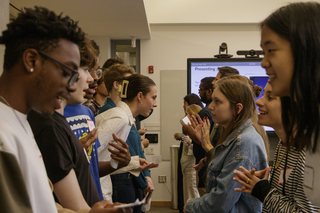Two lines of Writing Partners stand facing each other and talking during a training session.