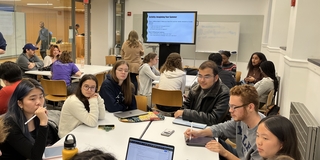 Students talk around a table during a class at the Poorvu Center.