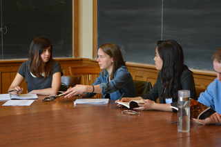 Three students sit at a table discussing a project together.