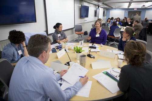 A group of Faculty Members discuss pedagogy during the Summer Institute on Course Redesign at a round table in the TEAL classroom.